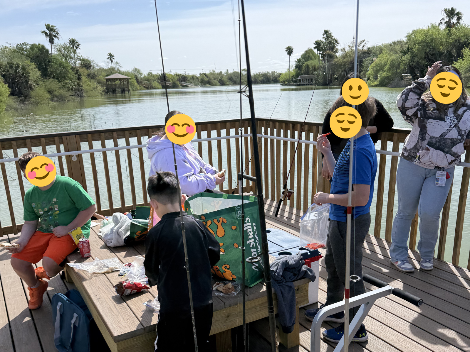 Children from Sunny Glen Children's Home enjoying a fishing outing on a wooden dock by a lake, surrounded by fishing rods and snacks, reflecting meaningful community experiences