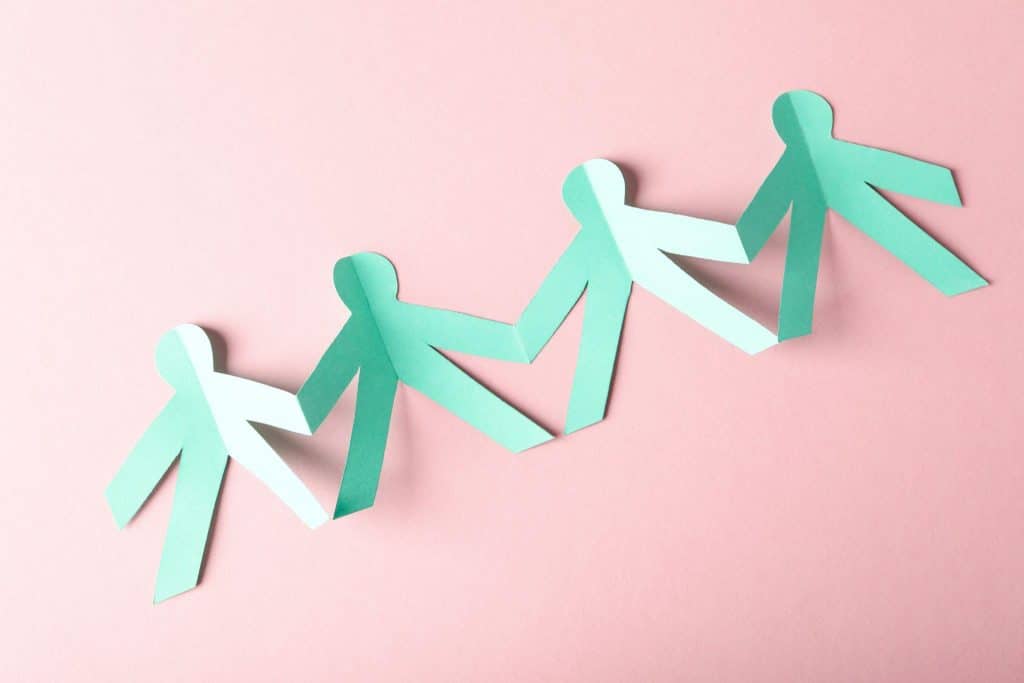 Paper cutout figures holding hands symbolizing long-term stability for children in organizational care.