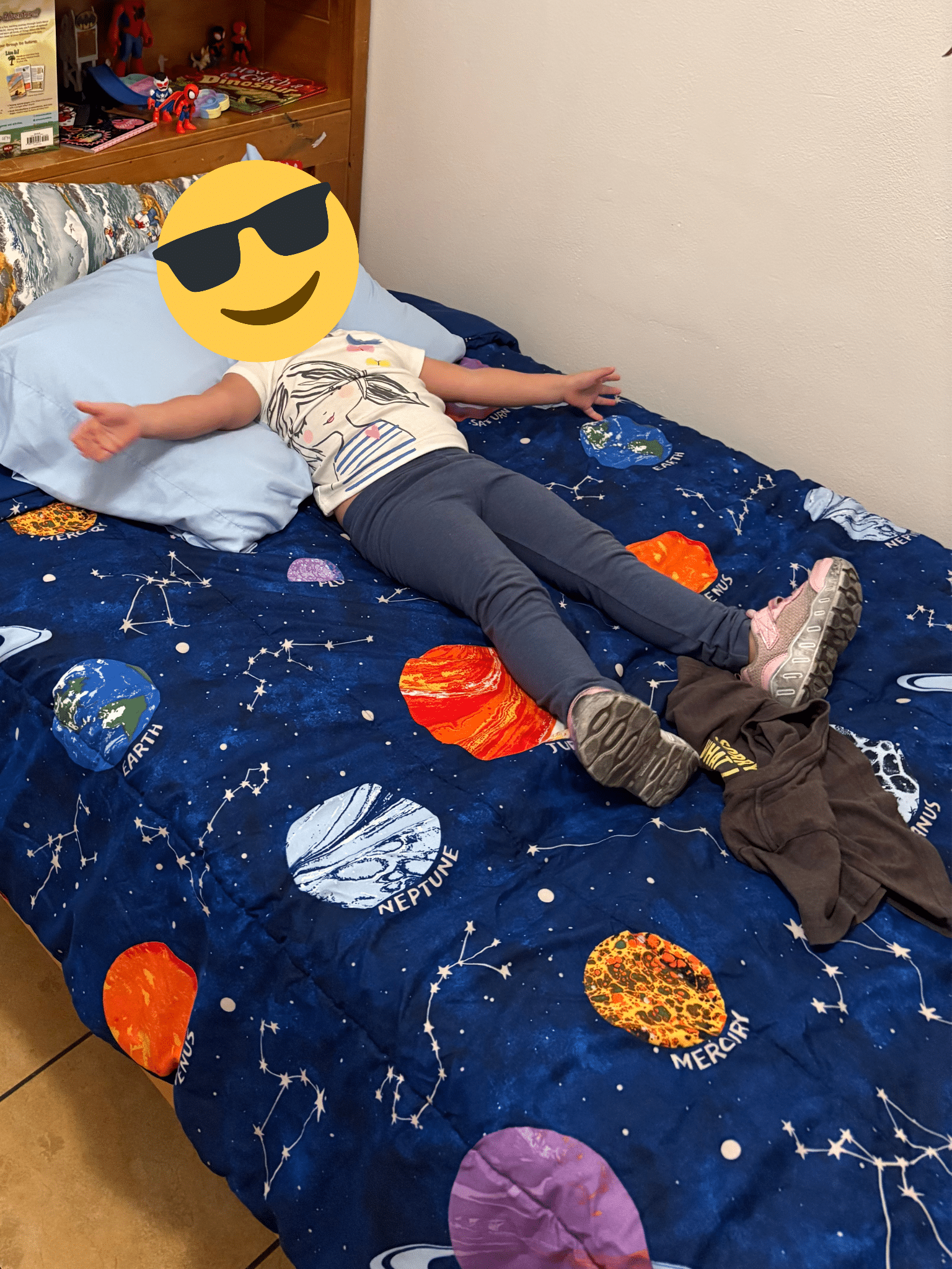 A child rests comfortably on a bed with space themed bedding during a day in the life at Sunny Glen, reflecting the safety, routine, and calm environment that helps children feel secure and cared for.