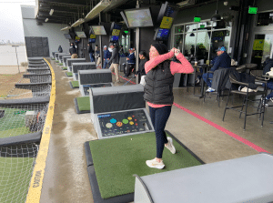 A participant takes a swing during a golf fundraiser at Topgolf Pharr, surrounded by community members coming together to support Sunny Glen Children’s Home and children across the Rio Grande Valley.