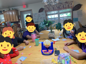 Children playing Bingo around a table, sharing laughter, focus, and connection