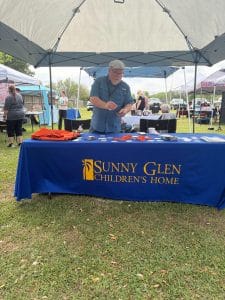 Mr. Craig Keel, Sunny Glen campus minister, arranges promotional items at the Baywood Church of Christ Community Afternoon Market booth.