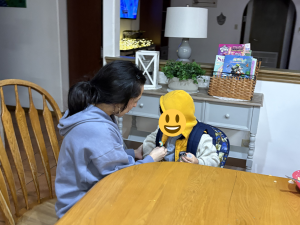 Caregiver sitting with a young child at a dining table inside a Sunny Glen home, reflecting the personal connection at the heart of faith-based child care.
